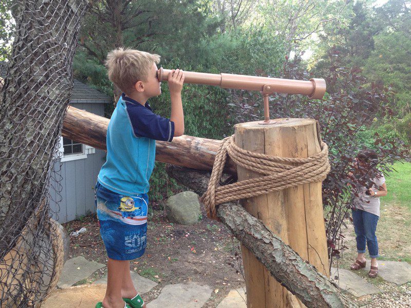 A young boy looking through a telescope at something.