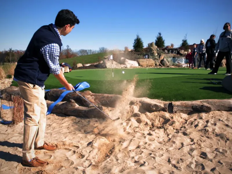 A man is playing golf on the sand