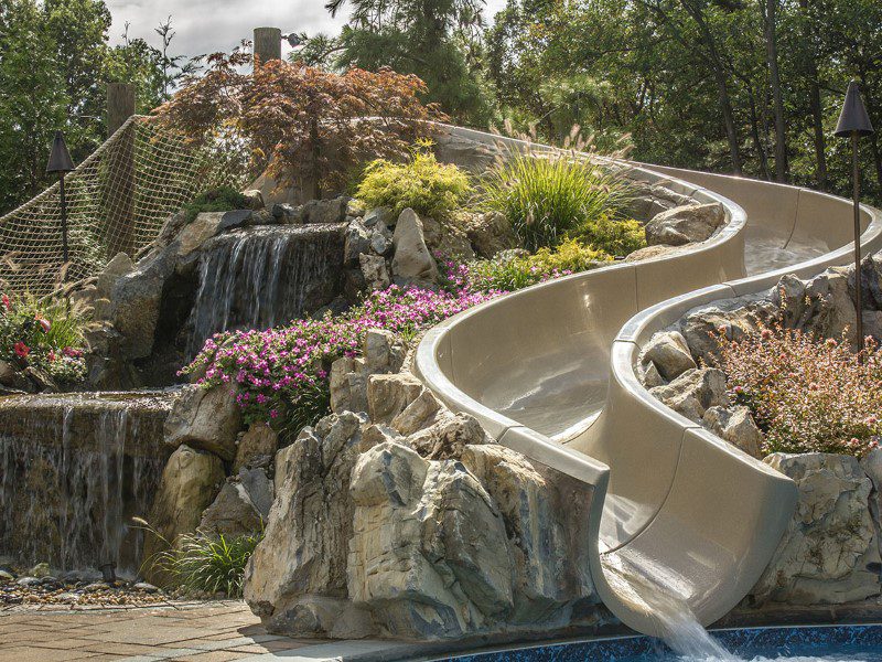 A slide in the middle of a pool with flowers around it.