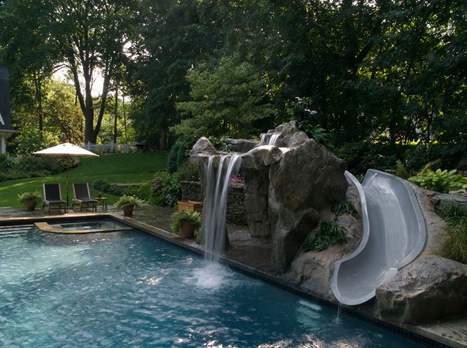 A pool with a slide and waterfall in the middle of it