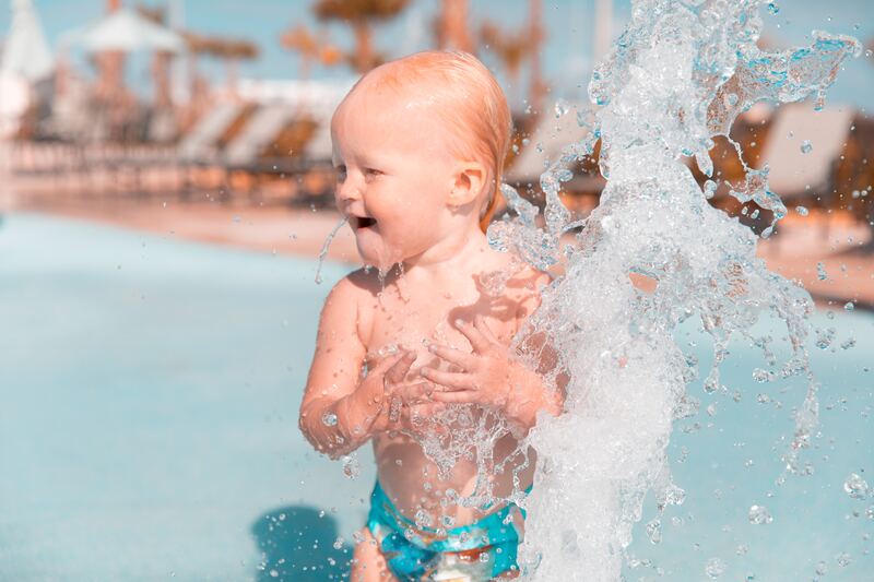 A baby is playing in the water at a pool.
