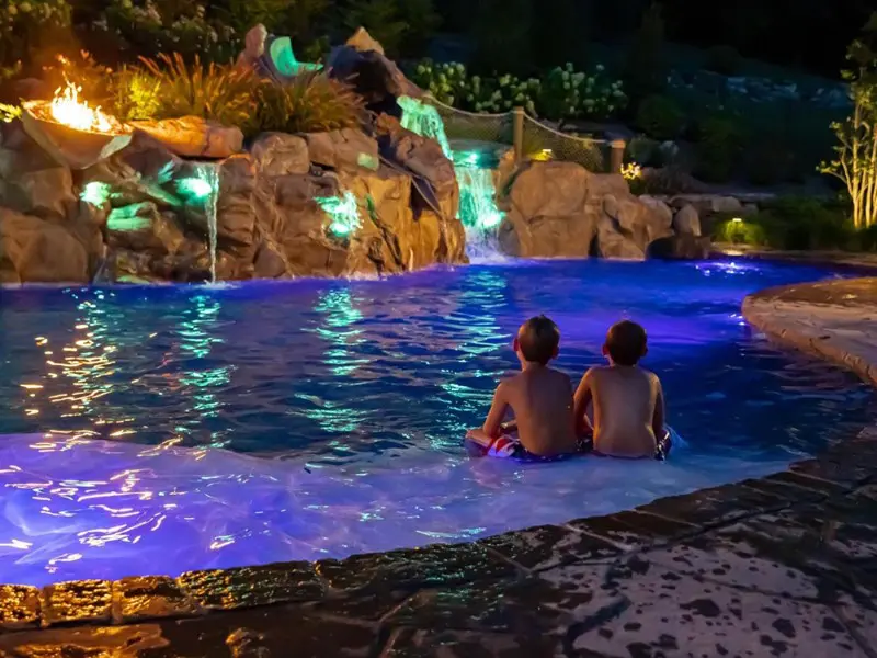 Two people sitting in a pool at night.