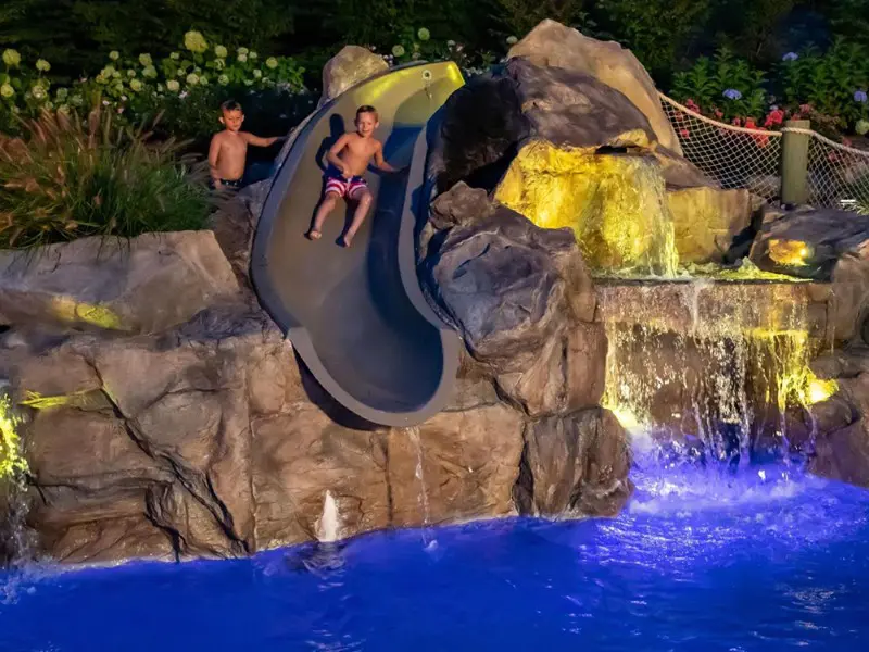Two kids on a slide in the water.