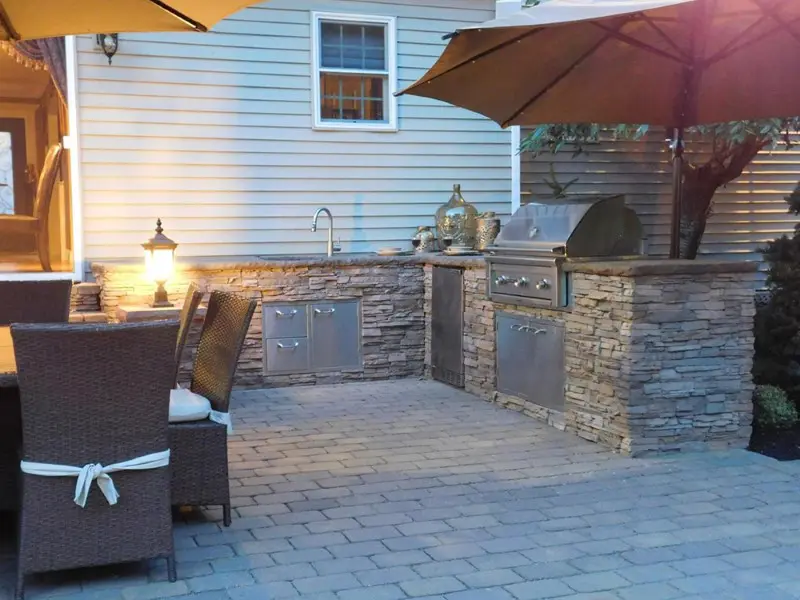 A patio with an outdoor grill and table.