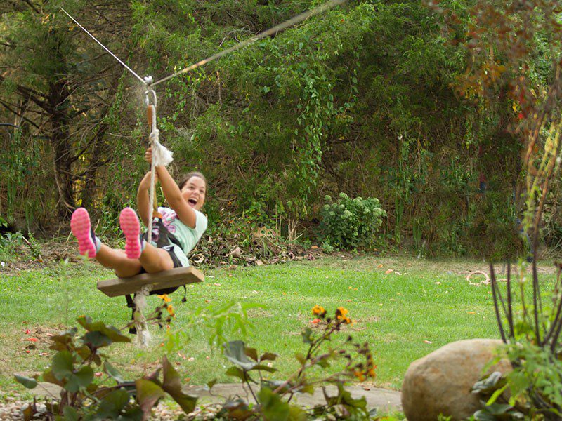 A girl is swinging on a rope swing.