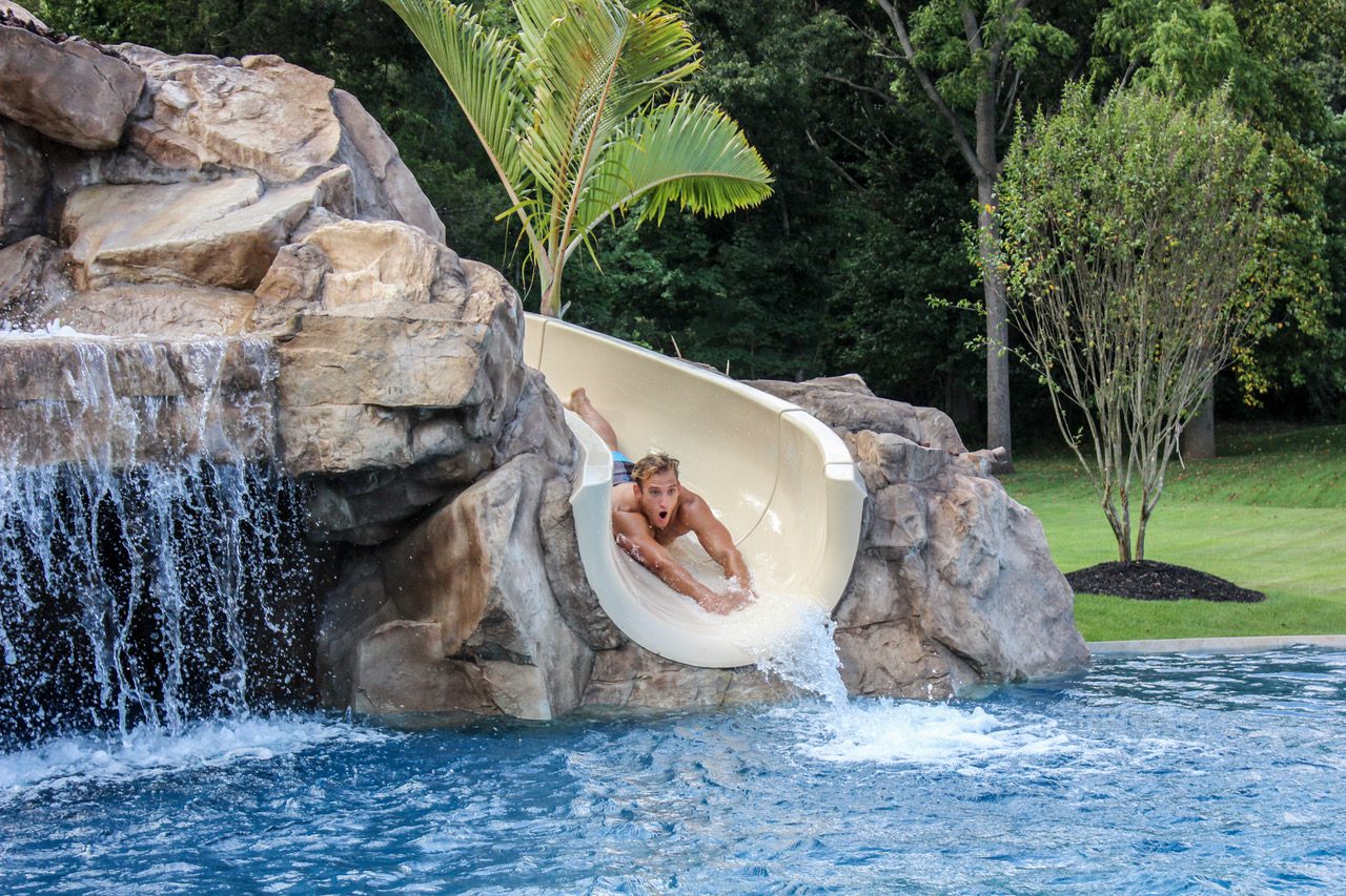 A man is sliding down the slide in the pool.