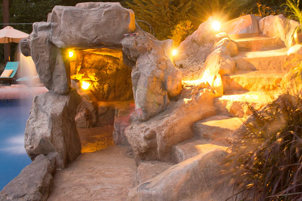 A stone cave with lights on the side of it.