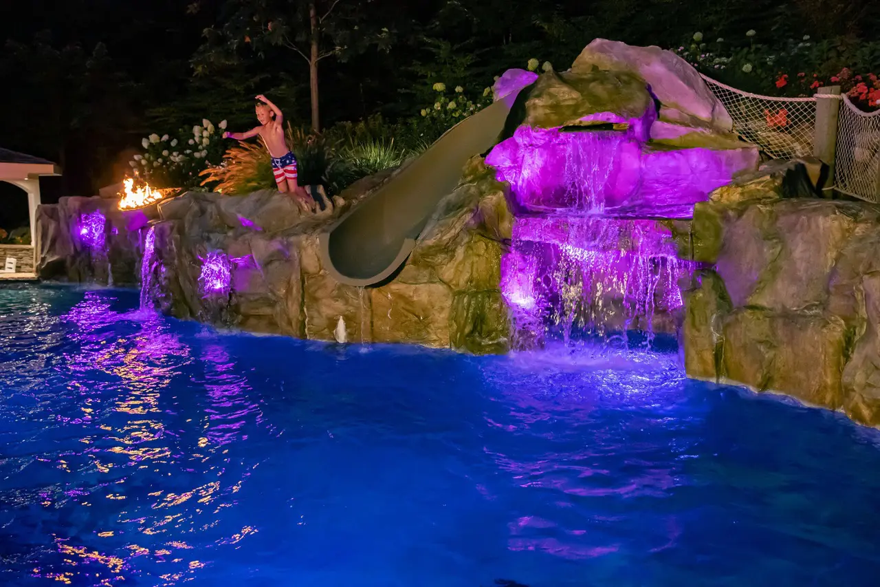 A person jumping into the pool at night