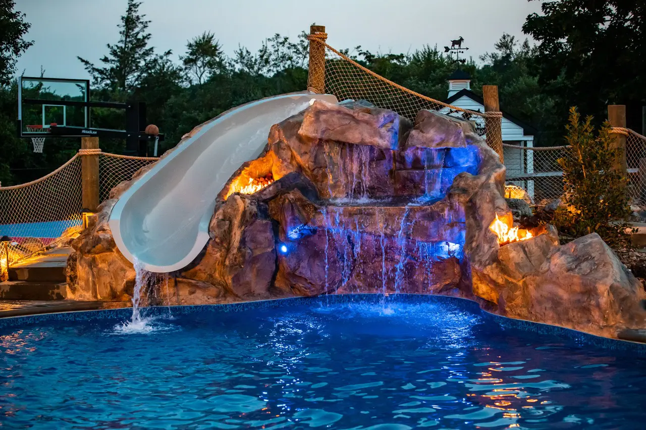 A pool with a slide and rock wall