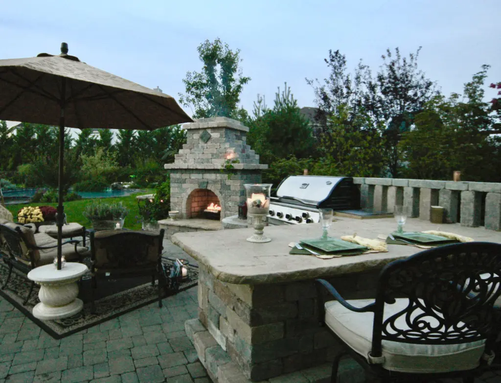 A patio with an outdoor fireplace and table.