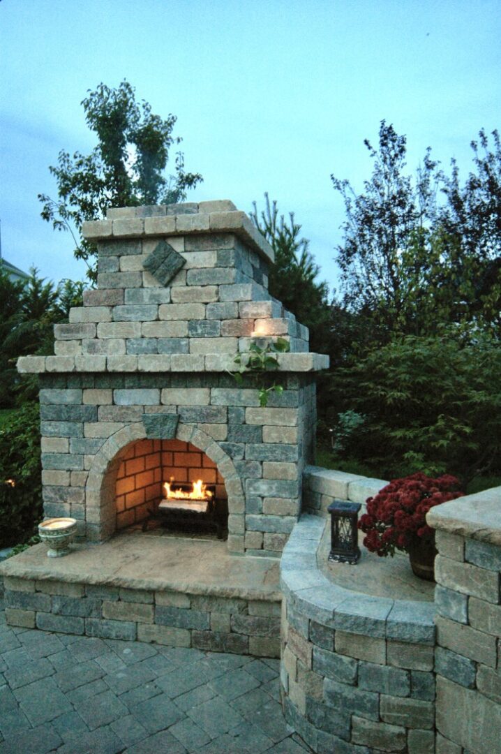 A stone fireplace in the middle of a garden.