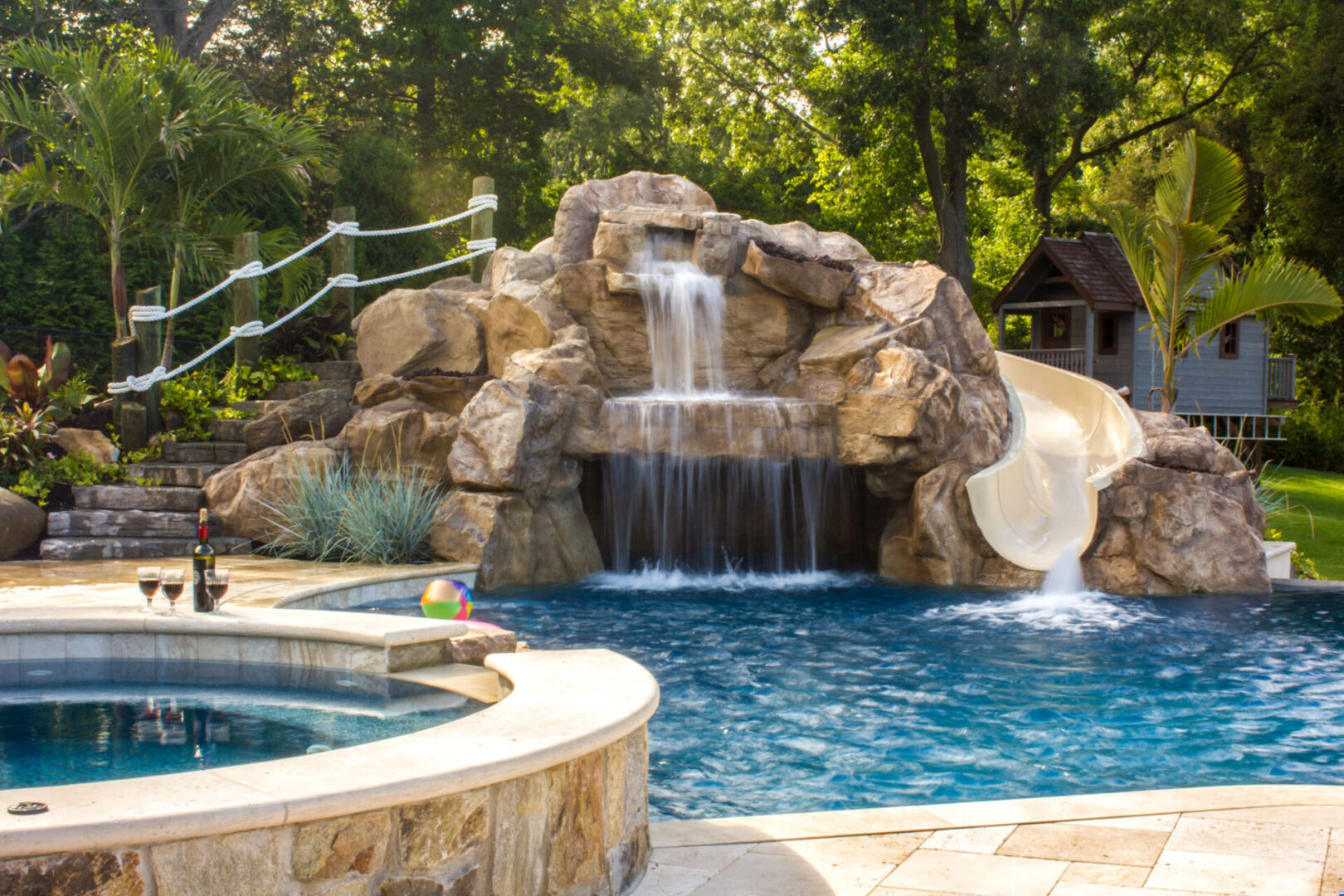 A pool with a slide and waterfall in the back ground