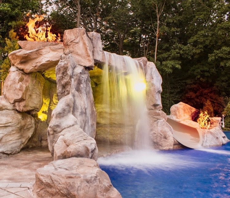 A pool with a waterfall and rocks in the background.