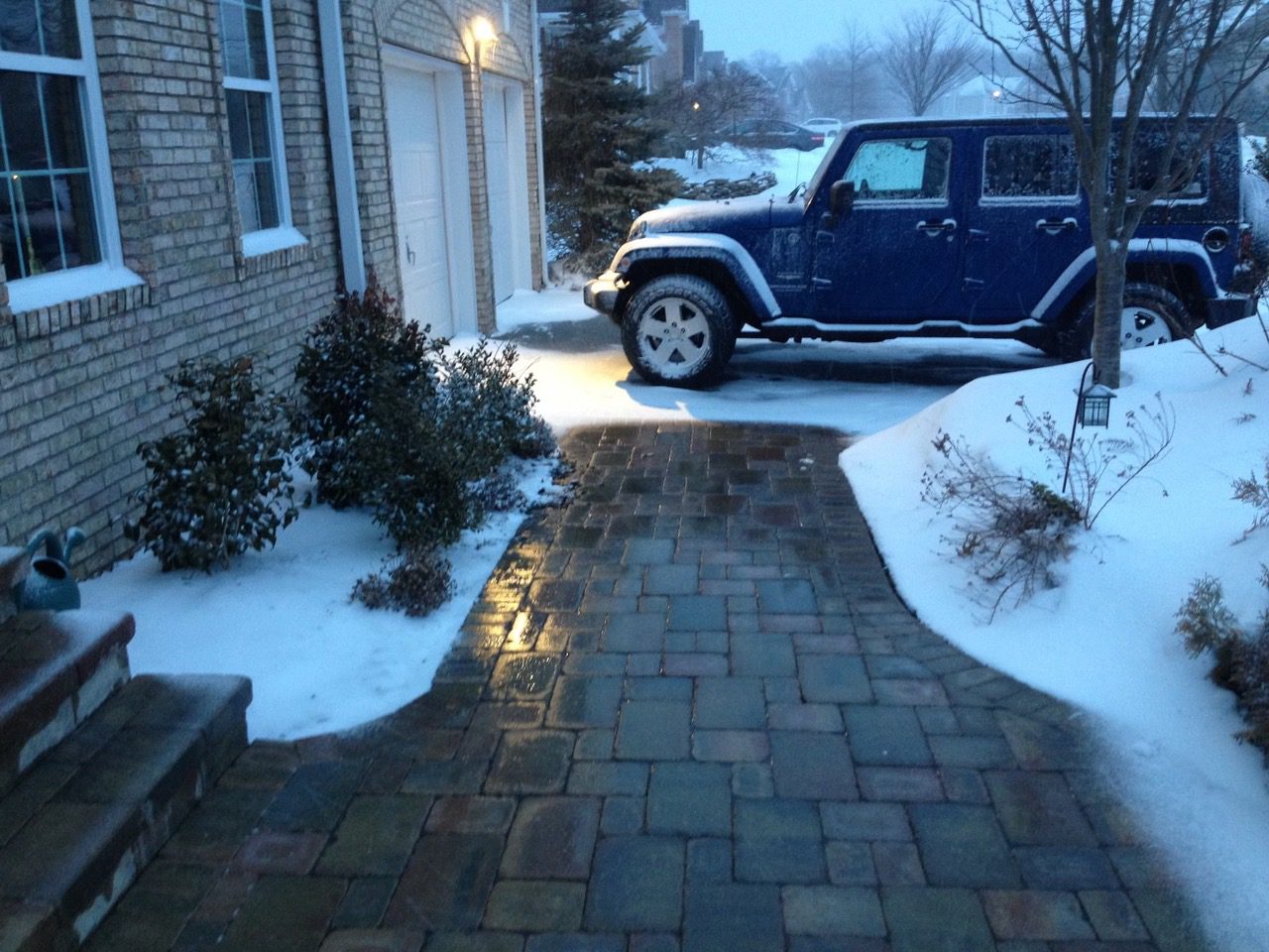 A blue jeep parked in the driveway of a house.