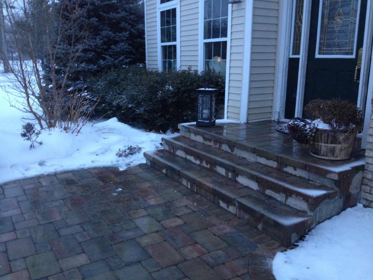 A porch with steps and snow on the ground.