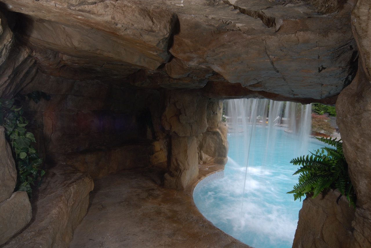 A cave with a waterfall and plants in it