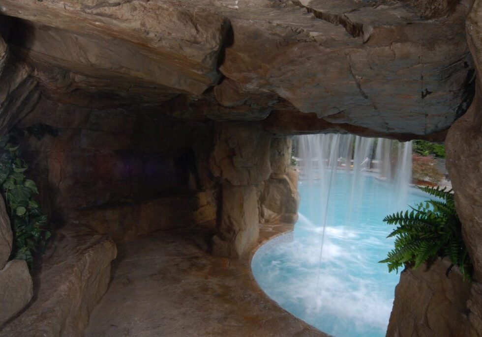 A cave with a waterfall and plants in it